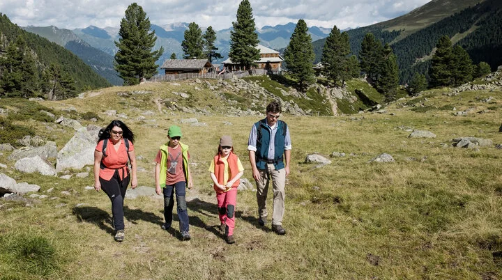 Eine Familie mit zwei kleinen Kindern wandert über eine Bergwiese | © DAV/Hans Herbig